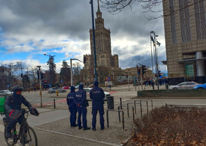 Trójka policjantów na tle Pałacu Kultury i Nauki w Warszawie
