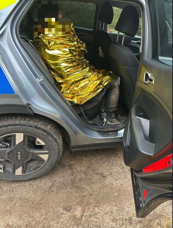 Na tylnym siedzeniu radiowozu osoba owinięta kocem termicznym