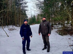 Policjant i strażnik leśny na tle ośnieżonego lasu
