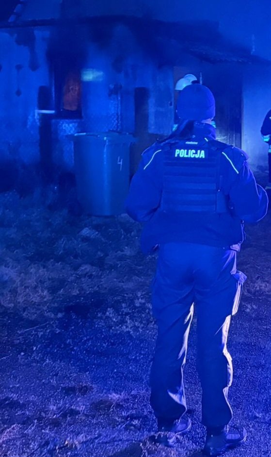W scenerii nocnej policjant na tle pogorzeliska