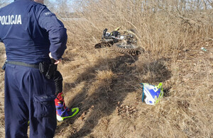 Leżący w krzakach motocykl terenowy obok policjant