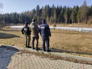 Policjant oraz dwójka strażników leśnych na parkingu leśnym