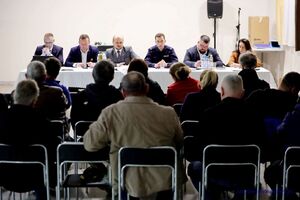 Sala konferencyjna wypełniona siedzącymi ludźmi, za stołem prezydialnym prelegenci