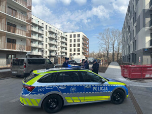 Trzech policjantów na nowym osiedlu mieszkaniowym, na pierwszym planie radiowóz