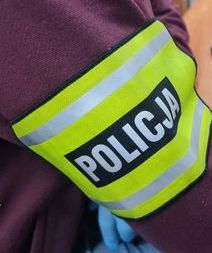 Ramię policjanta z opaską odblaskową z napisem Policja