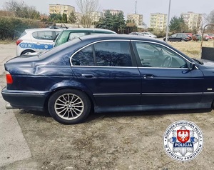 Granatowy samochód osobowy, w tle radiowóz