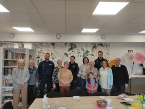 Trójka policjantów oraz grupa seniorów pozująca do zdjęcia w świetlicy