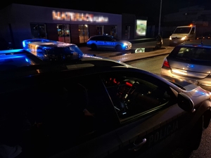 W scenerii nocnej ulicy zbliżenie galeryjki radiowozu z włączonymi sygnałami świetlnymi