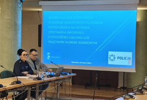 Mężczyzna w marynarce oraz policjantka podczas prelekcji, na pierwszym planie prezentacja Power Point