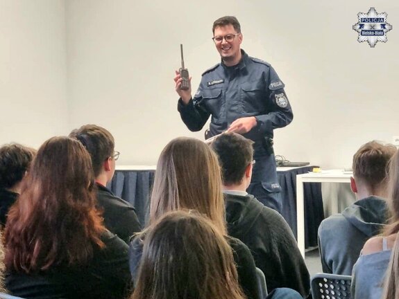 Uśmiechnięty policjant podczas prelekcji dla młodzieży