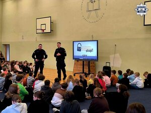 Dwóch policjantów podczas prelekcji dla zgromadzonej w sali gimnastycznej młodzieży