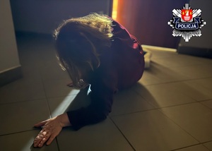 Leżąca na posadzce korytarza starsza kobieta