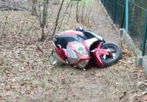 Przewrócony w krzakach obok ogrodzenia motorower