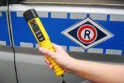 Ręka trzymająca alkotest na tle radiowozu