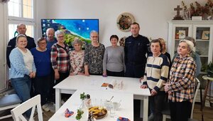 Dwóch policjantów oraz grupa seniorów pozująca do zdjęcia w świetlicy