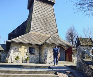 Policjant idący w kierunku wejścia do strzelistego kościoła z kamienia pokrytego gontem