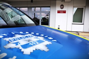 Zbliżenie maski radiowozu z logiem policji na tle komisariatu
