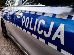 Zbliżenie boku radiowozu z napisem policja