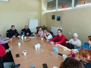 Dwaj policjanci przy stole wraz z grupą osób w różnym wieku