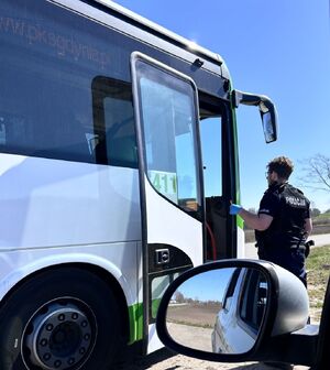 Policjant przy otwartych drzwiach autobusu komunikacji miejskiej