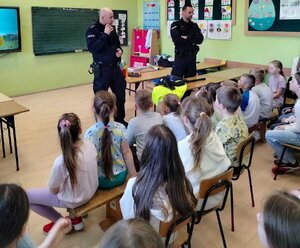 W sali szkolnej dwóch policjantów podczas pogadanki dla grupy małych dzieci
