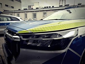 Przód radiowozu stojącego na wewnętrznym parkingu przy budynku Policji