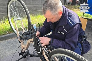 Policjant kucający przy odwróconym do góry kołami rowerze