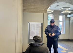 Policjant legitymujący mężczyznę w poczekalni dworcowej