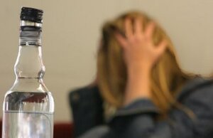 Rozmyte zdjęcie kobiety z długimi włosami, na pierwszym planie butelka wódki
