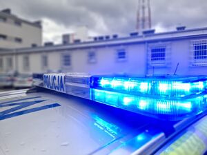 Zbliżenie tzw. galeryjki na dachu radiowozu, w tle rozmyte kontury budynków