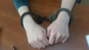 Zbliżenie rąk leżących na biurku z nałożonymi kajdankami