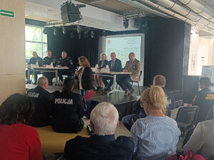 Sala konferencyjna wypełniona mieszkańcami, widoczni umundurowani policjanci