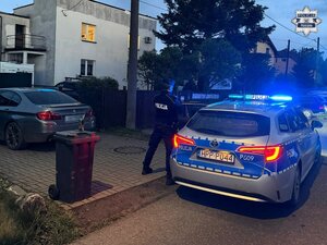 W scenerii wieczoru policjant przy radiowozie na terenie zakładu napraw samochodów