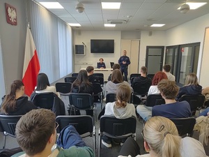 Dwójka policjantów podczas prelekcji dla młodzieży siedzącej w klasie