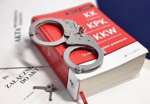 Kajdanki leżące na kodeksie karnym i obwolucie akt