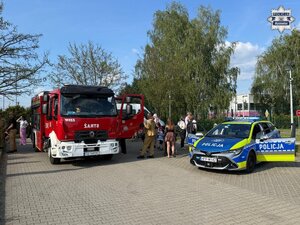 Radiowóz i wóz strażacki na placu oglądane przez dzieci i młodzież