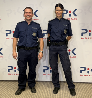 Dwójka uśmiechniętych policjantów na tle ścianki Polskiego radia PiK
