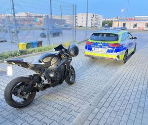 Na placu marketu czarny motocykl na tle radiowozu