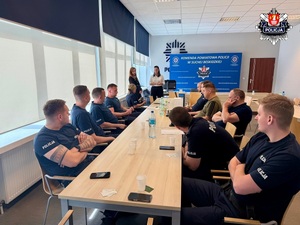 Dwie kobiety prowadzące prelekcję dla policjantów siedzących przy stole konferencyjnym