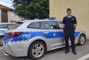 Policjant na tle radiowozu