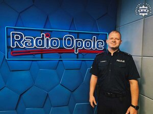 Uśmiechnięty policjant na tle ścianki radia opole