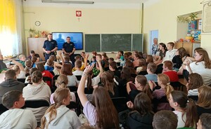 Dwaj policjanci podczas prelekcji dla licznie zgromadzonej młodzieży w klasie szkolnej