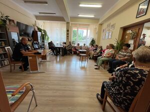 Policjant podczas prelekcji w sali wypełnionej seniorami