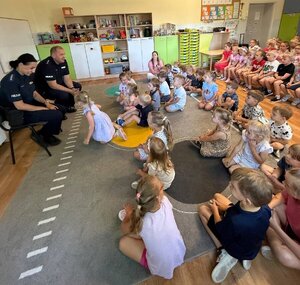 Dwójka policjantów prowadząca pogadankę dla dzieci w sali przedszkolnej