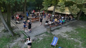 Na leśnej polanie widziane z góry duża grupa osób na pikniku