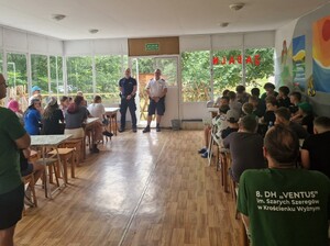 Dwaj policjanci podczas prelekcji dla zgromadzonej w jadalni harcerskiej młodzieży.