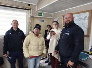 Dwie uśmiechnięte kobiety oraz dwóch policjantów pozujących do zdjęcia w małym pomieszczeniu