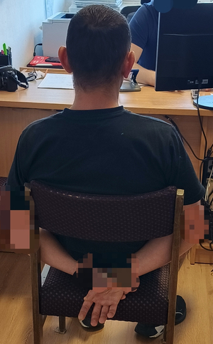 Zbliżenie z tyłu mężczyzny ze skutymi kajdankami rękami siedzącego na krześle
