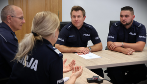 Przy stole konferencyjnym dwóch młodych policjantów oraz starszy oficer i kobieta generał