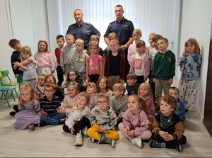 Wewnątrz sali dwaj policjanci oraz grupa dzieci pozująca do zdjęcia